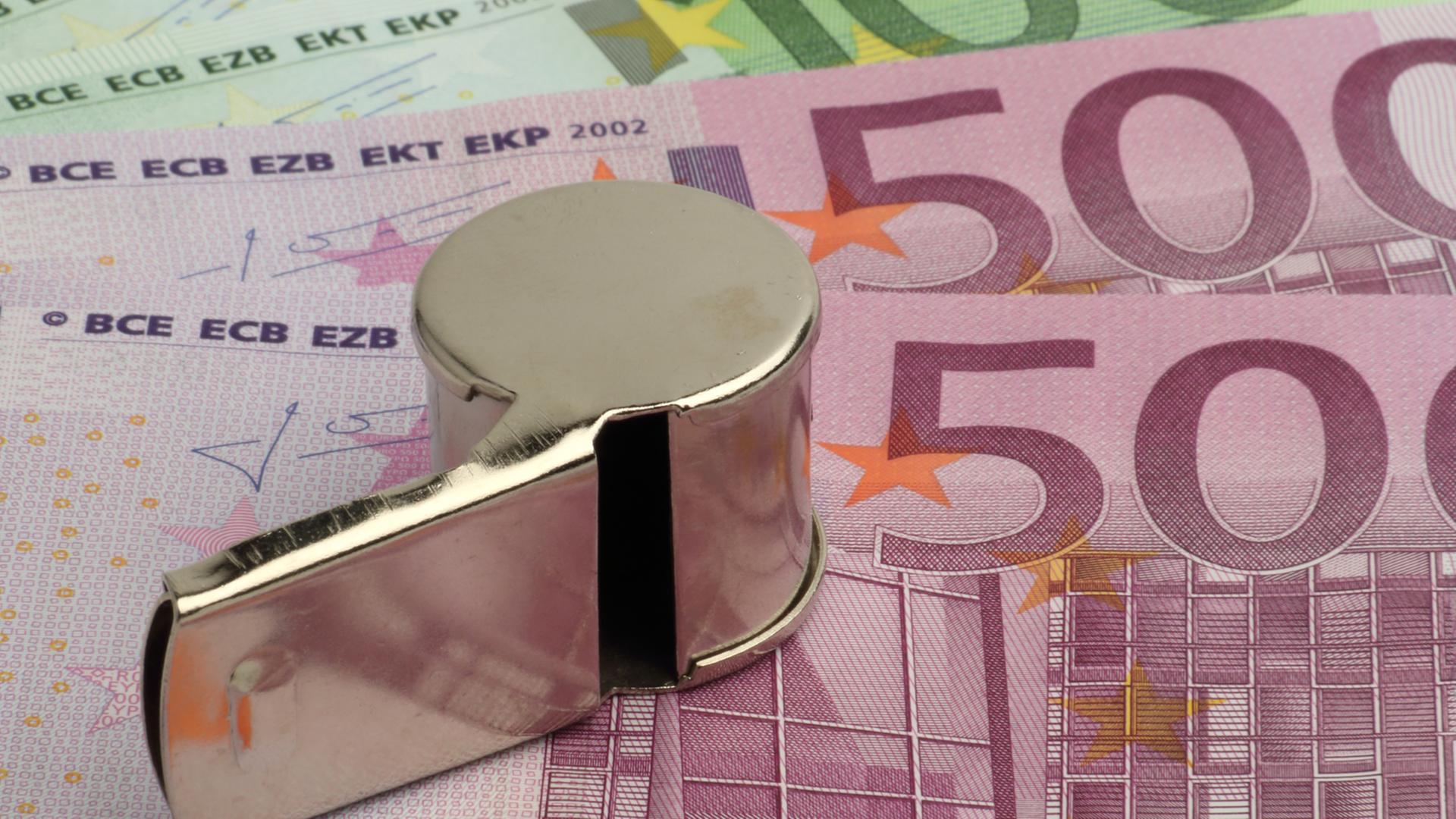 Eine Trillerpfeife liegt auf mehreren 500-Euro-Scheinen. Eine Trillerpfeife liegt auf mehreren 500-Euro-Scheinen.