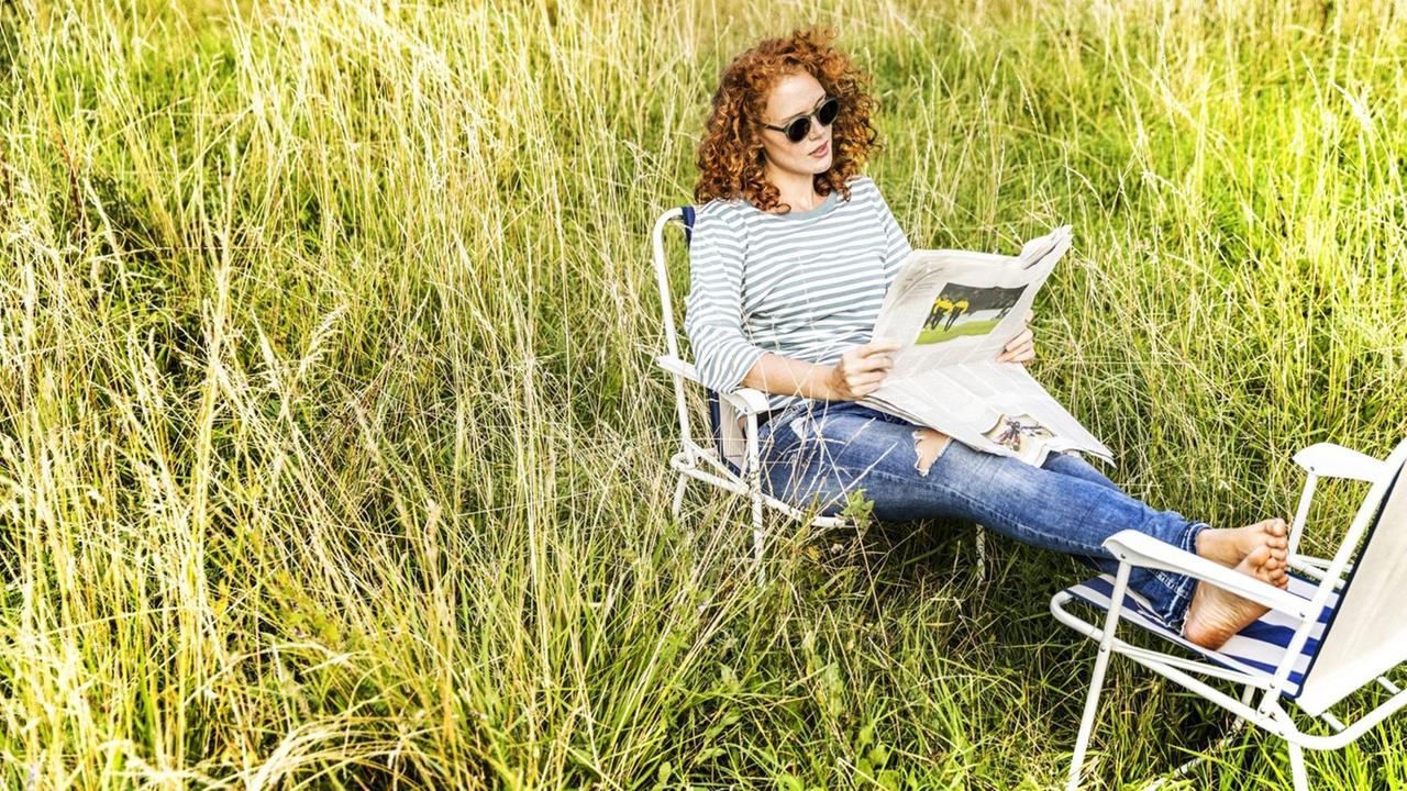 Eine Frau im Grünen liest Zeitung Eine Frau im Grünen liest Zeitung