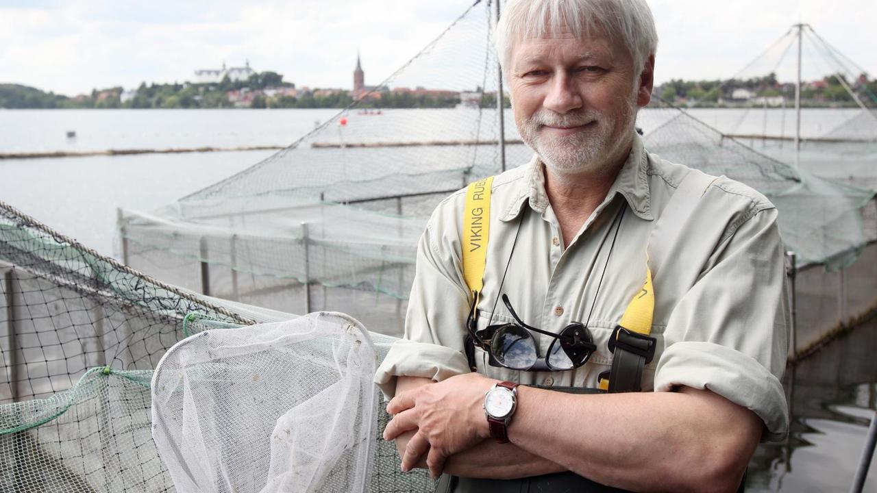 Der Direktor des Max-Planck-Instituts für Evolutionsbiologie, Manfred Milinski, steht am Rande des Plöner Sees ineben großen Käfigen, in denen sich Stichlinge tummeln.