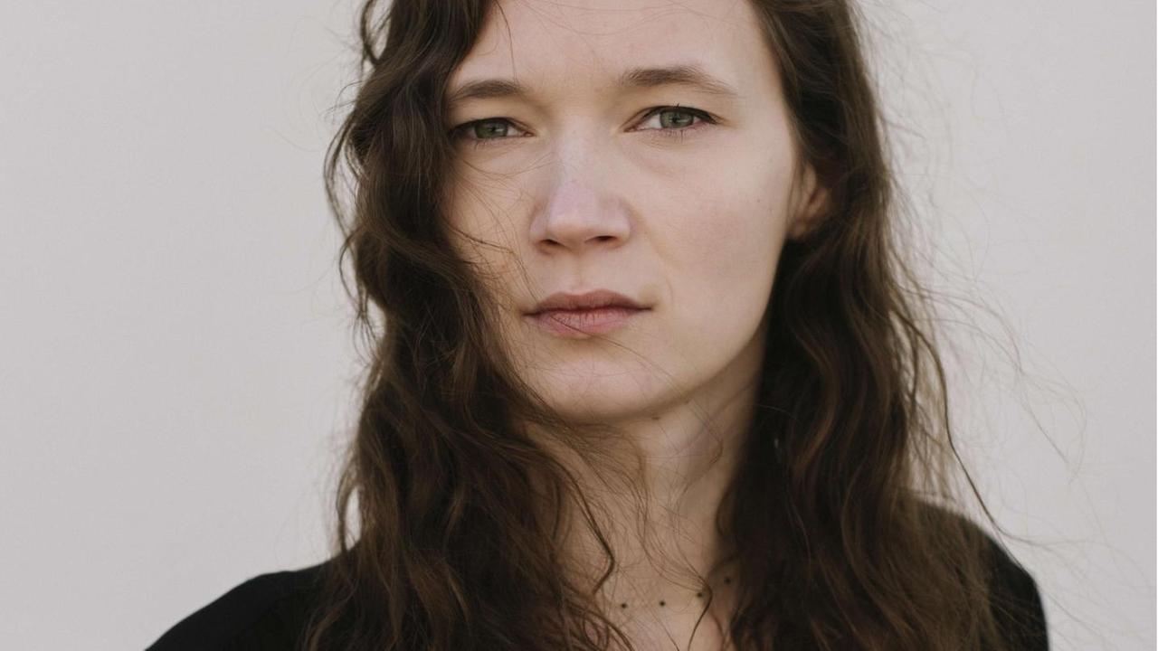 Die Autorin Anna Mayr steht vor einer Wand und schaut ernst in die Kamera Die Autorin Anna Mayr steht vor einer Wand und schaut ernst in die Kamera