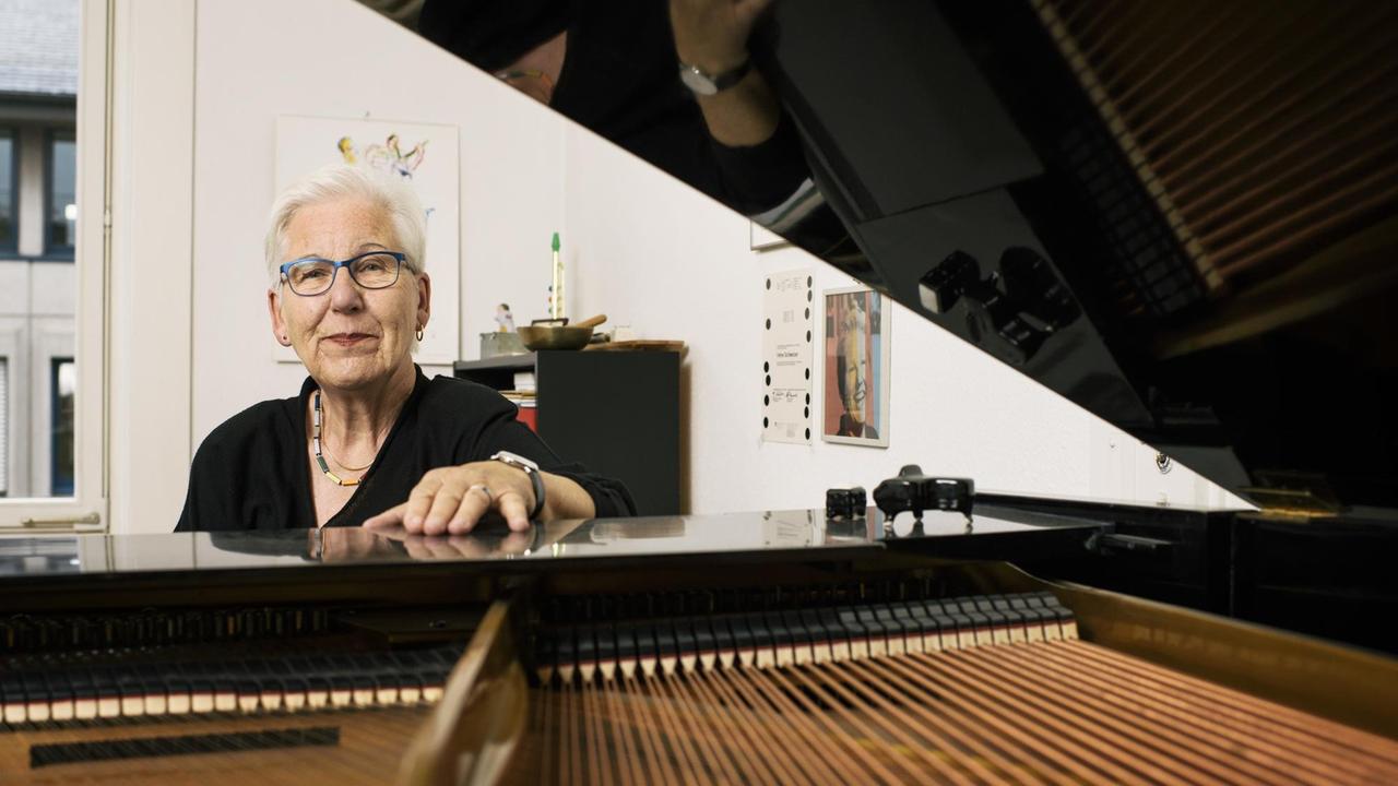 Irene Schweizer sitzt an ihrem Flügel und schaut freundlich in die Kamera. Irene Schweizer sitzt an ihrem Flügel und schaut freundlich in die Kamera.