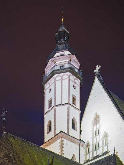 Abendstimmung um die Kirche, deren heller Turm erstrahlt.