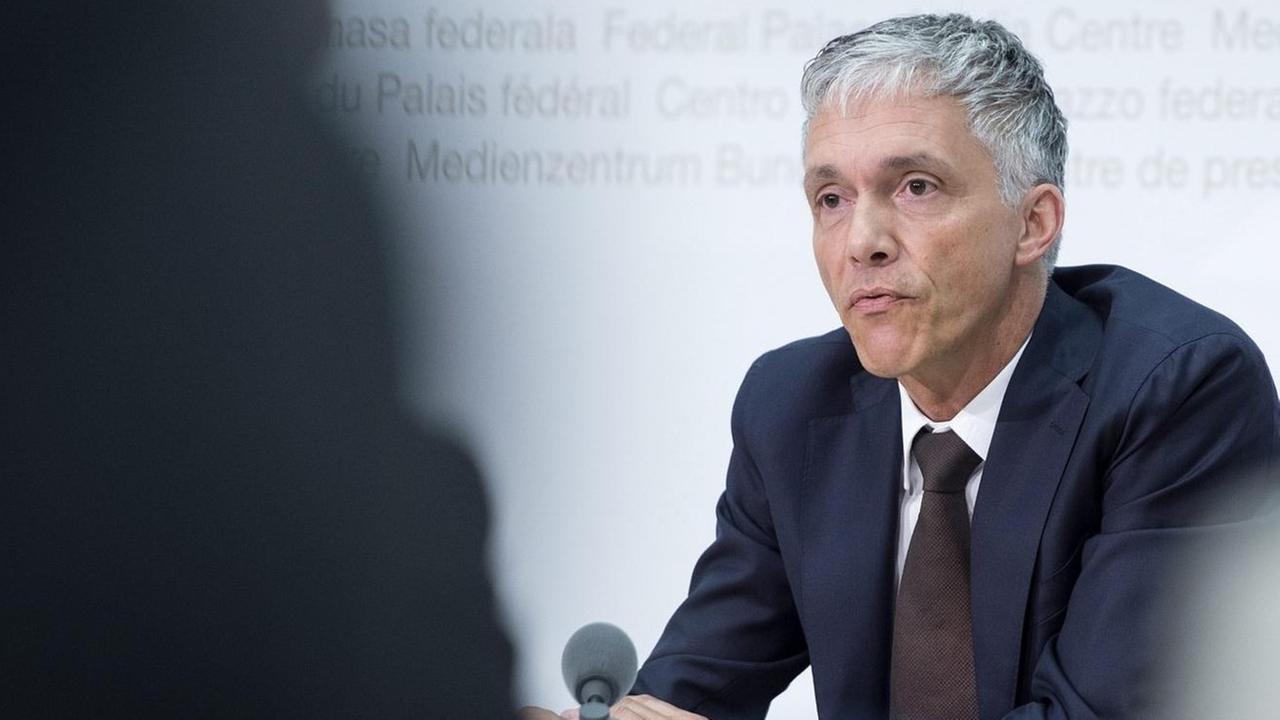 Foto vom oberste Strafermittler der Schweiz, Michael Lauber, bei einer Pressekonferenz durch zwei Journalisten hindurch Foto vom oberste Strafermittler der Schweiz, Michael Lauber, bei einer Pressekonferenz durch zwei Journalisten hindurch