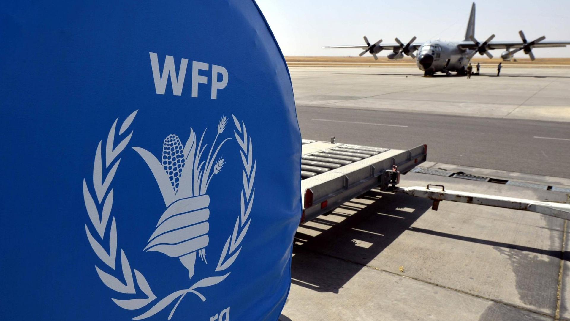 Ein Logo des Welternährungsprogramms World Food Programme und ein belgisches Militärflugzeug auf einem Rollfeld im irakischen Erbil, August 2014 Ein Logo des Welternährungsprogramms World Food Programme und ein belgisches Militärflugzeug auf einem Rollfeld im irakischen Erbil, August 2014