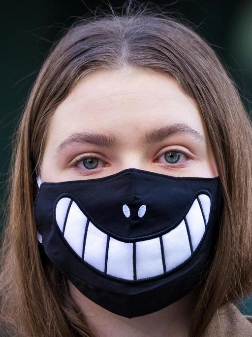 Ein Mädchen trägt eine Halloween-Maske vor dem Gesicht, als Schutz vor dem Corona Virus. London, 16. März 2020