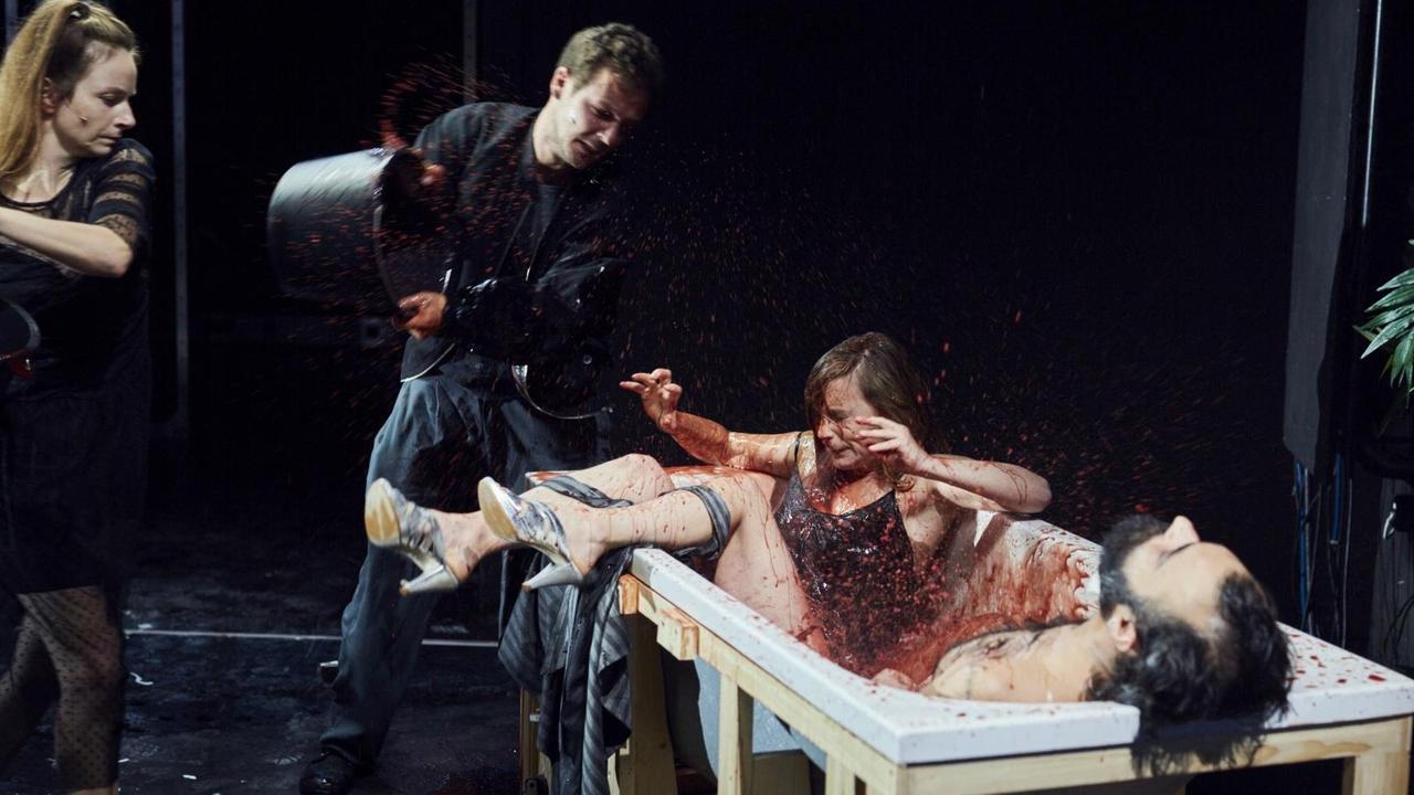 Ein Mann kippt Blut in eine Wanne mit zwei Personen. Ein Mann kippt Blut in eine Wanne mit zwei Personen.