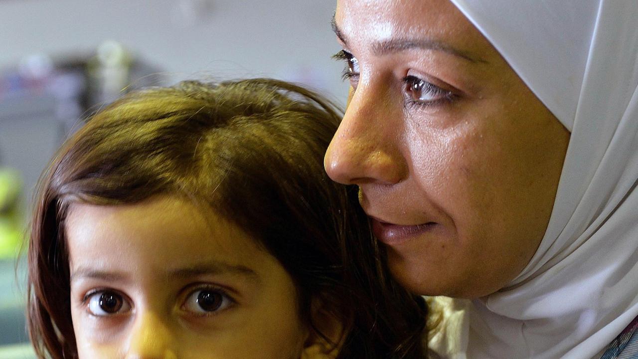 Eine Frau mit Kopftuch mit Kind auf dem Schoß - sie gehörten zur ersten syrischen Flüchtlingsgruppe, die im September 2013 in Hannover gelandet ist.