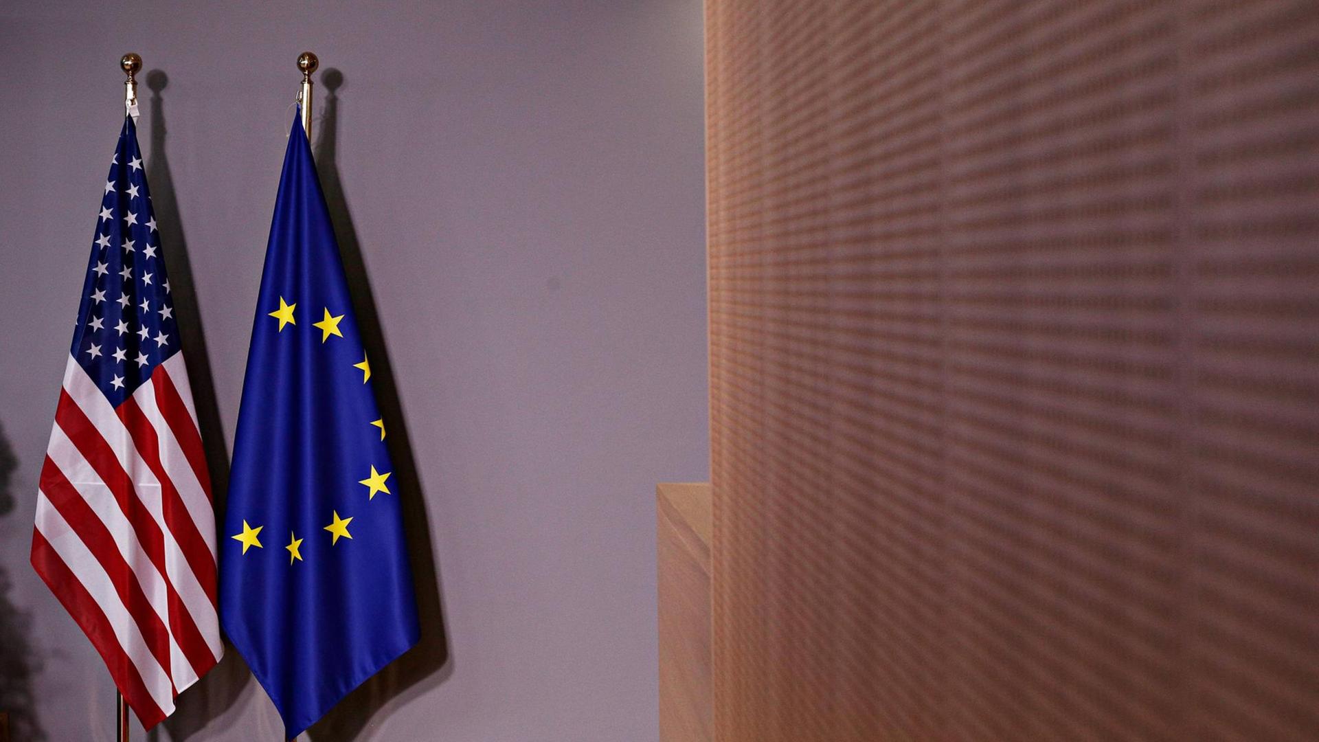 Die Flaggen der EU und der USA stehen vor einem Treffen von US-Präsident Donald Trump und EU-Kommissionspräsident Jean Claude Juncker in einem Raum Die Flaggen der EU und der USA stehen vor einem Treffen von US-Präsident Donald Trump und EU-Kommissionspräsident Jean Claude Juncker in einem Raum