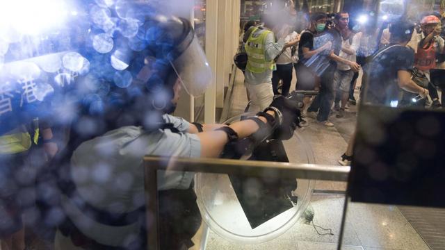 Dramatische, unübersichtliche Szene eines Polizisten, der seine Waffe in einem Terminal auf einen Aktivisten richtet