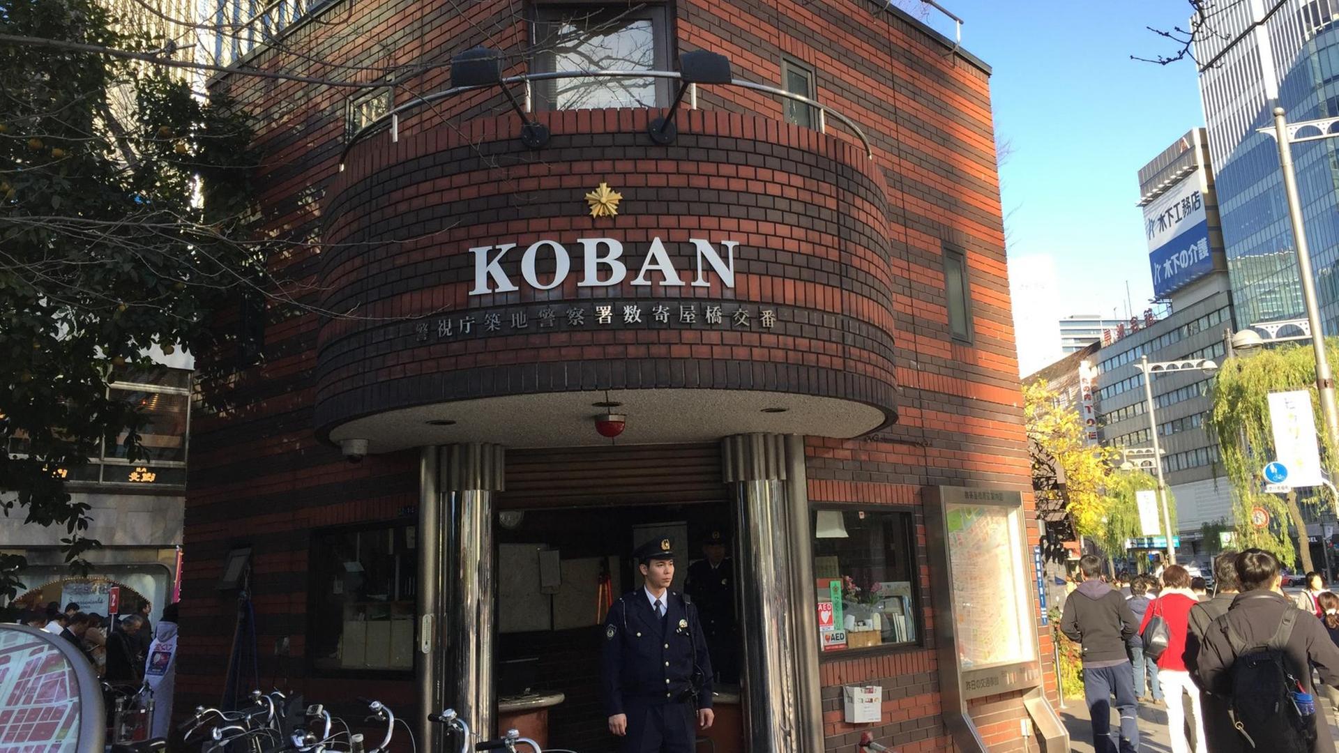 Ein Koban (japanische Mini-Polizeiwache) im Tokioter Bezirk Ginza mit dazugehörigem Polizisten davor. Auf dem Land wohnen die Bezirkspolizisten sogar in ihren Häuschen.