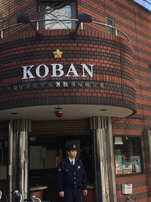 Ein Koban (japanische Mini-Polizeiwache) im Tokioter Bezirk Ginza mit dazugehörigem Polizisten davor. Auf dem Land wohnen die Bezirkspolizisten sogar in ihren Häuschen.