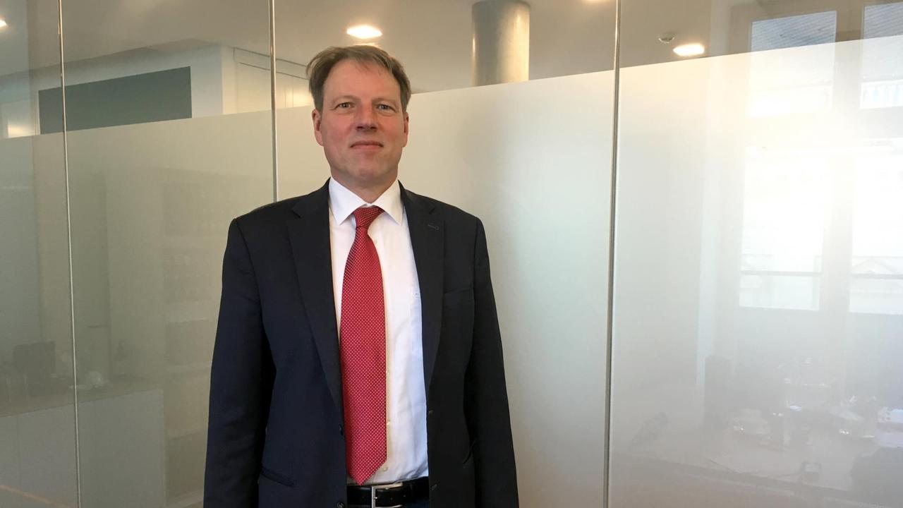 Dr. Stefan Bach steht vor einer Glaswand und schaut in die Kamera. Dr. Stefan Bach steht vor einer Glaswand und schaut in die Kamera.