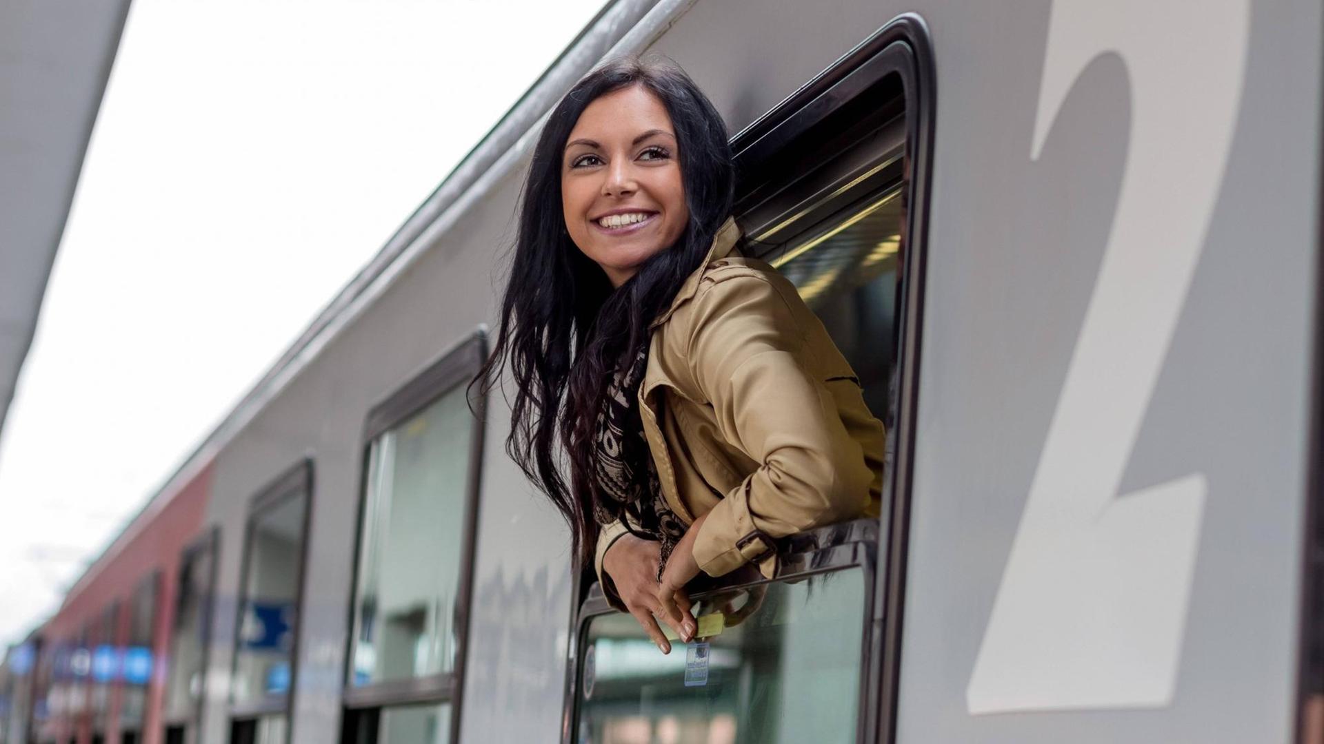 Eine Frau schaut aus dem Fenster eines Zuges im Bahnhof Eine Frau schaut aus dem Fenster eines Zuges im Bahnhof