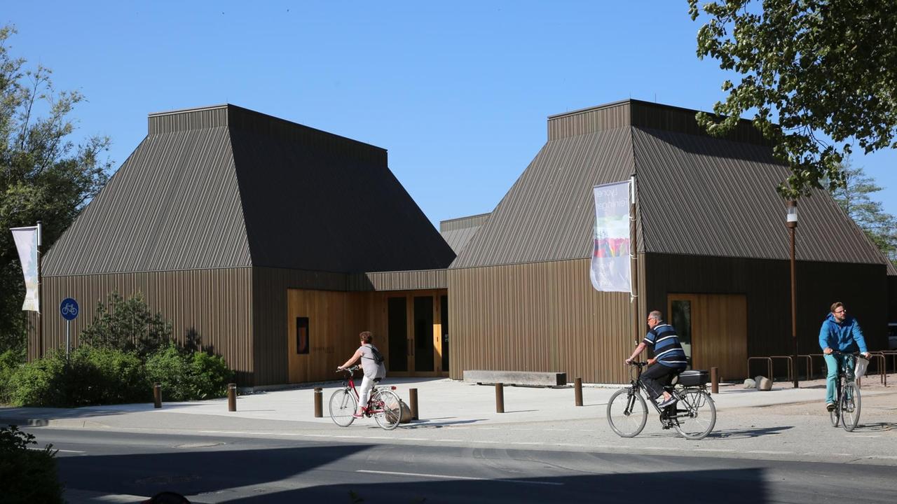 Das Kunstmuseum in Ahrenshoop in der Frontansicht. Dvor fahren Fahrradfahrer vorbei. Das Kunstmuseum in Ahrenshoop in der Frontansicht. Dvor fahren Fahrradfahrer vorbei.