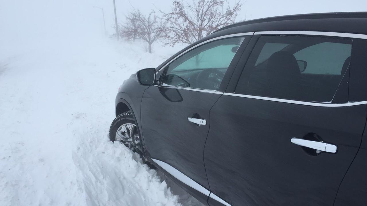 Ein schwarzes Auto steckt im hohen Schnee fest. Ein schwarzes Auto steckt im hohen Schnee fest.