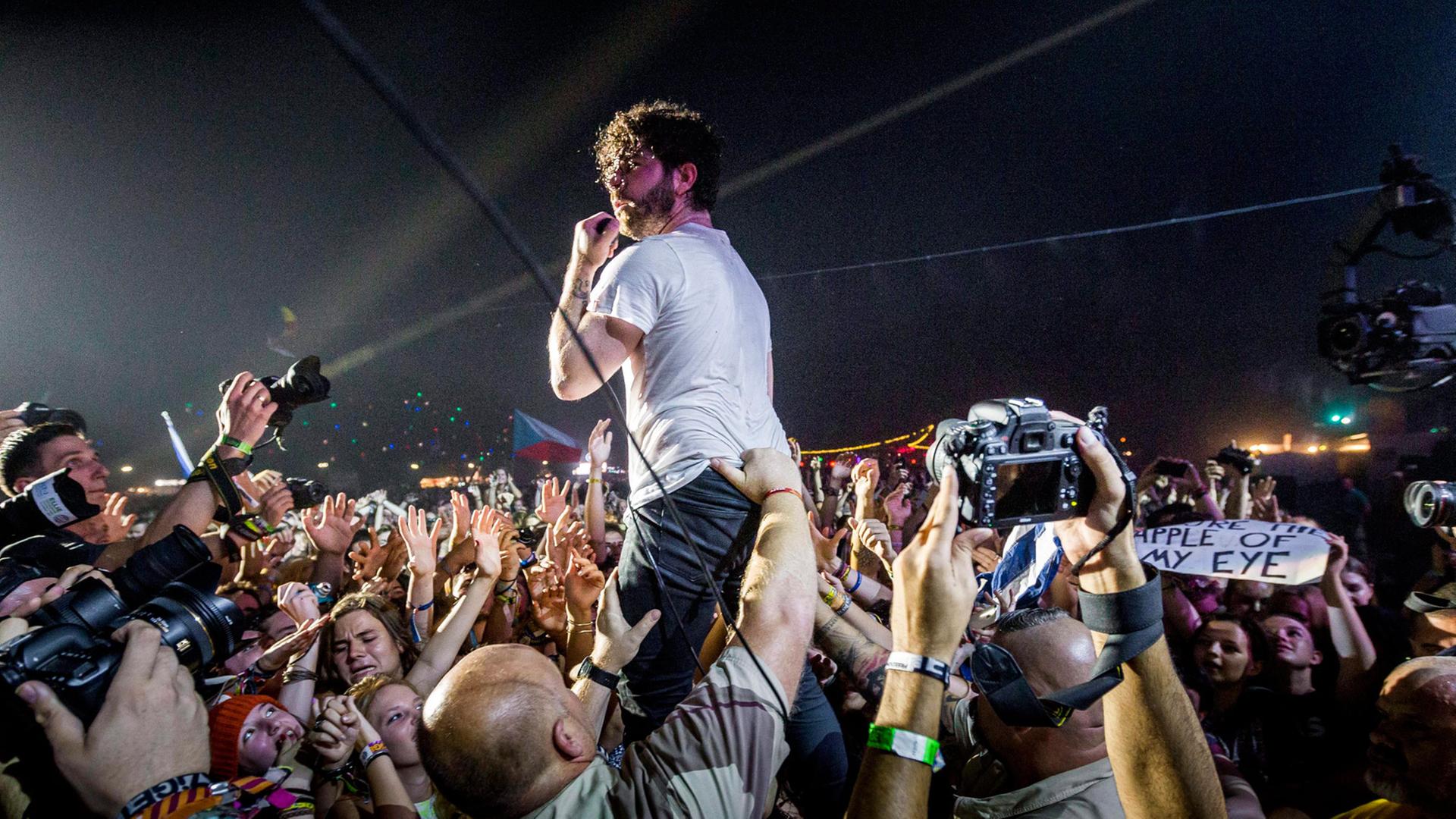 Sänger und Gtarrist Yannis Philippakis während eines Konzerts der Indie-Band "Foals" am 13. August 2015. Fans jubeln dem ihm zu, er steht ganz nahe bei ihnen. Sänger und Gtarrist Yannis Philippakis während eines Konzerts der Indie-Band "Foals" am 13. August 2015. Fans jubeln dem ihm zu, er steht ganz nahe bei ihnen.