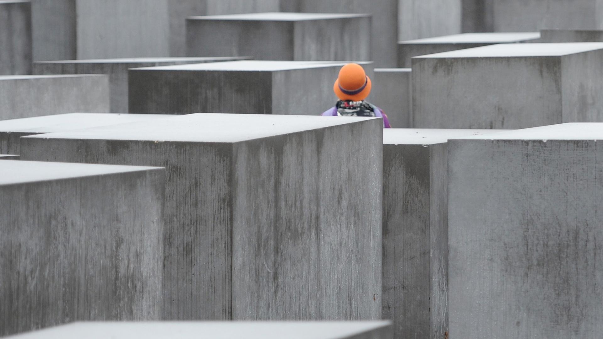 Eine Frau mit buntem Hut steht am 09.12.2013 in Berlin im Nieselregen zwischen den Stelen des Holocaust-Mahnmals in Berlin. Eine Frau mit buntem Hut steht am 09.12.2013 in Berlin im Nieselregen zwischen den Stelen des Holocaust-Mahnmals in Berlin.