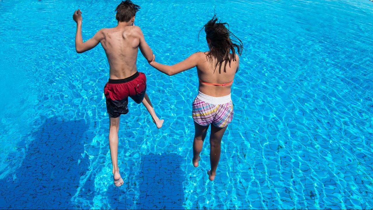 Ein Junge und ein Mädchen springen gemeinsam in ein Schwimm-Becken. Ein Junge und ein Mädchen springen gemeinsam in ein Schwimm-Becken.