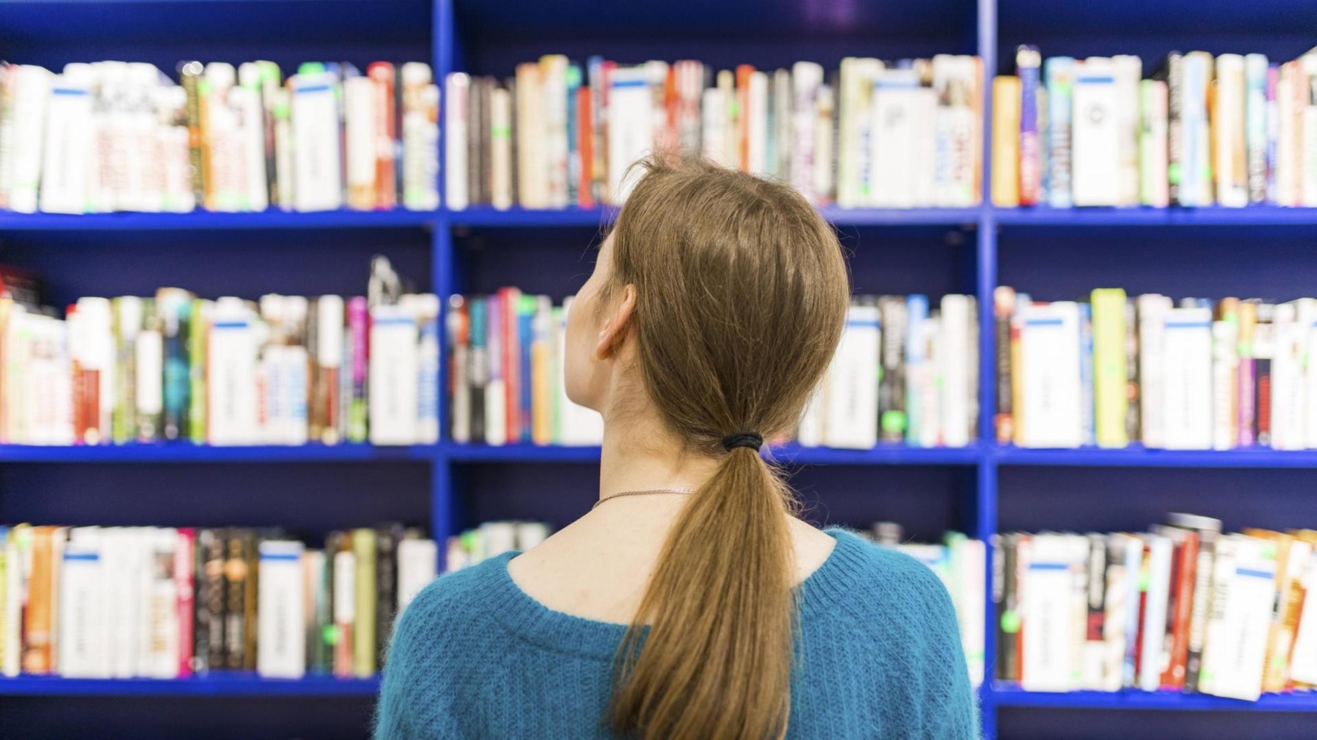 Eine Frau steht vor Bücherregalen.