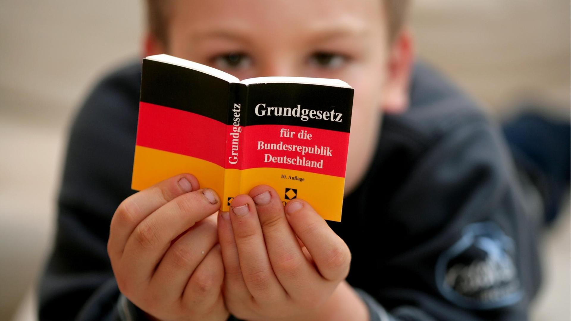 Ein Kind liest in einem Mini-Grundgesetz. Ein Kind liest in einem Mini-Grundgesetz.