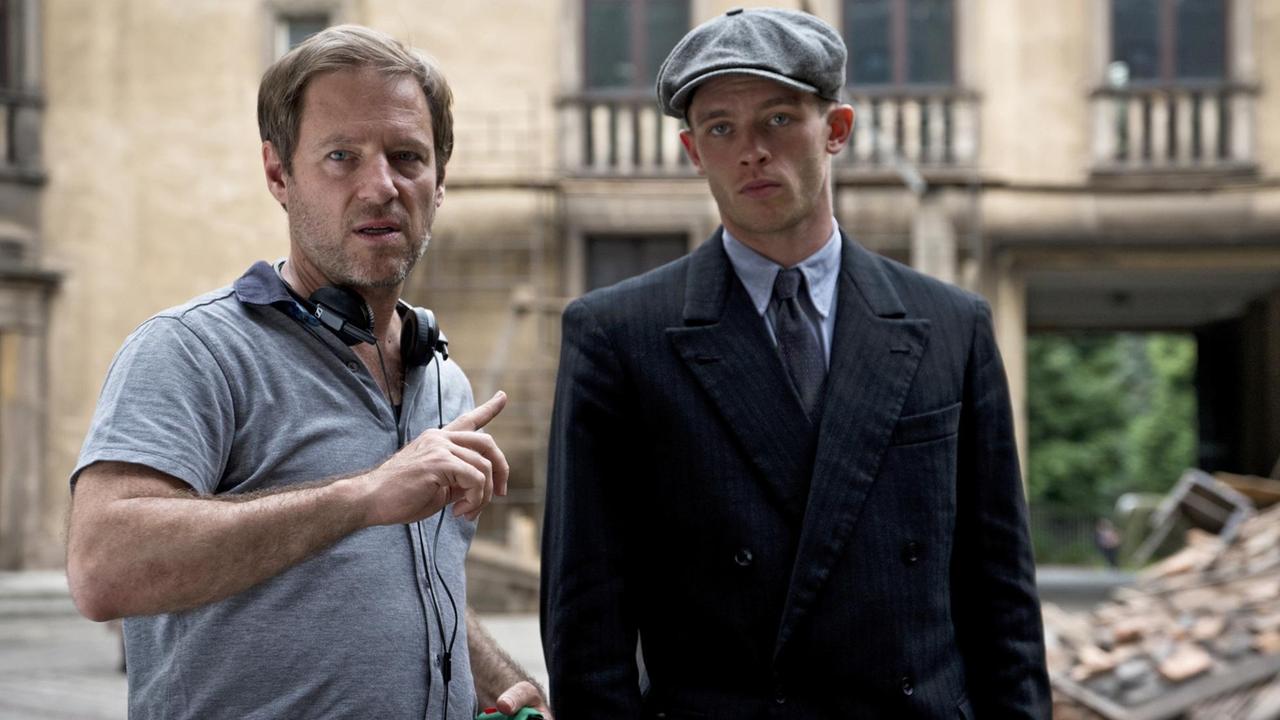 Der Regisseur steht in lockerer Kleidung in einem Hof und gibt seinem Schauspieler in historischer Kleidung Anweisungen. Der Regisseur steht in lockerer Kleidung in einem Hof und gibt seinem Schauspieler in historischer Kleidung Anweisungen.