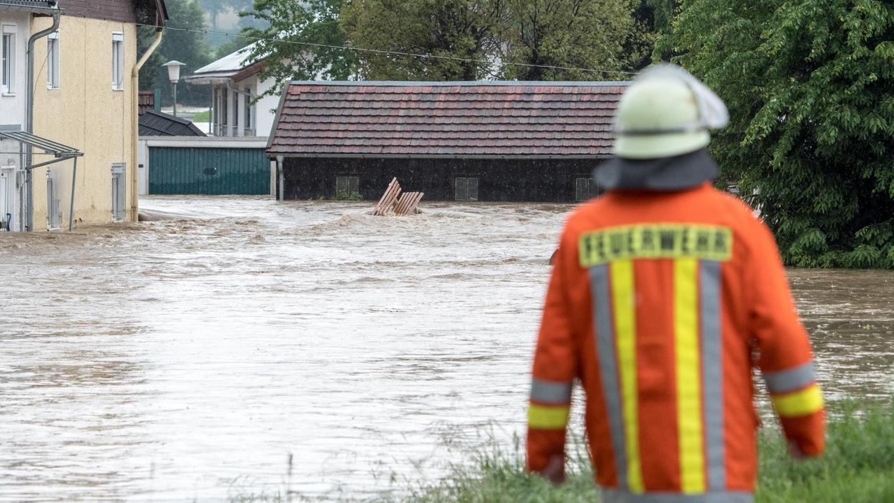 Ein Feuerwehrmann steht am 01.06.2016 in Triftern (Bayern) vor Häusern im Hochwasser. 
