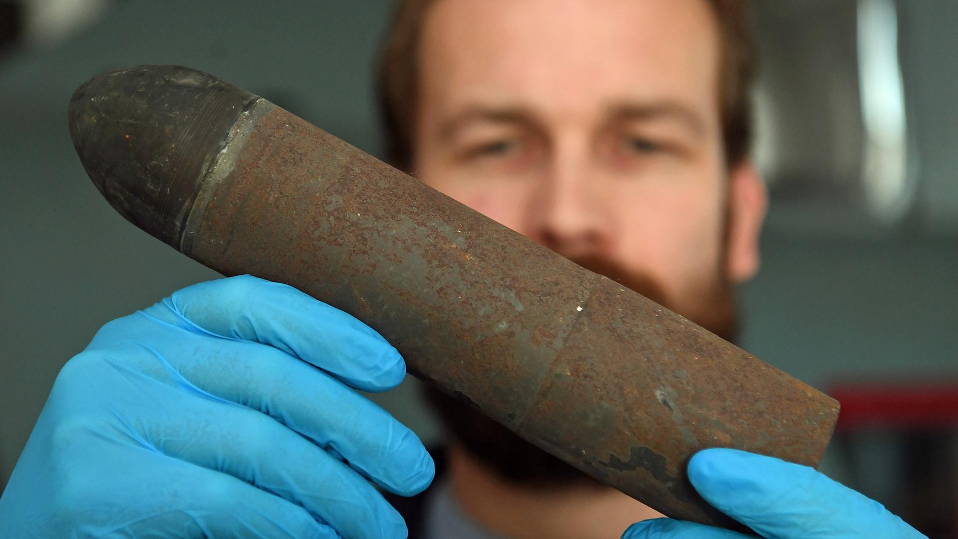 Philipp Grassel, wissenschaftlicher Mitarbeiter im Bereich Maritime Archäologie im Schifffahrtsmuseum Bremerhaven, hält eine Geschosshülse in seinen Händen. Er arbeitet in einem Forschungsprojekt, das sich der Problematik von verklappter Munition, Kriegswracks und der daraus resultierenden Umweltverschmutzung in der Nordsee widmet. Philipp Grassel, wissenschaftlicher Mitarbeiter im Bereich Maritime Archäologie im Schifffahrtsmuseum Bremerhaven, hält eine Geschosshülse in seinen Händen. Er arbeitet in einem Forschungsprojekt, das sich der Problematik von verklappter Munition, Kriegswracks und der daraus resultierenden Umweltverschmutzung in der Nordsee widmet.