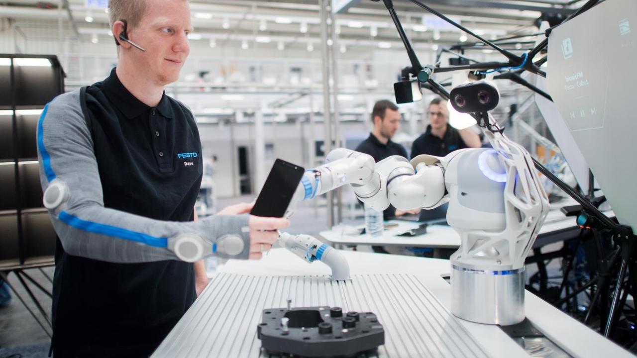 22.04.2018, Niedersachsen, Hannover: Entwickler Christian Trapp interagiert bei der Hannover Messe am Stand von Festo mit einem Roboterarm. Festo zeigt mit dem BionicWorkplace einen Arbeitsplatz für die Mensch-Roboter-Kollaboration. 22.04.2018, Niedersachsen, Hannover: Entwickler Christian Trapp interagiert bei der Hannover Messe am Stand von Festo mit einem Roboterarm. Festo zeigt mit dem BionicWorkplace einen Arbeitsplatz für die Mensch-Roboter-Kollaboration.