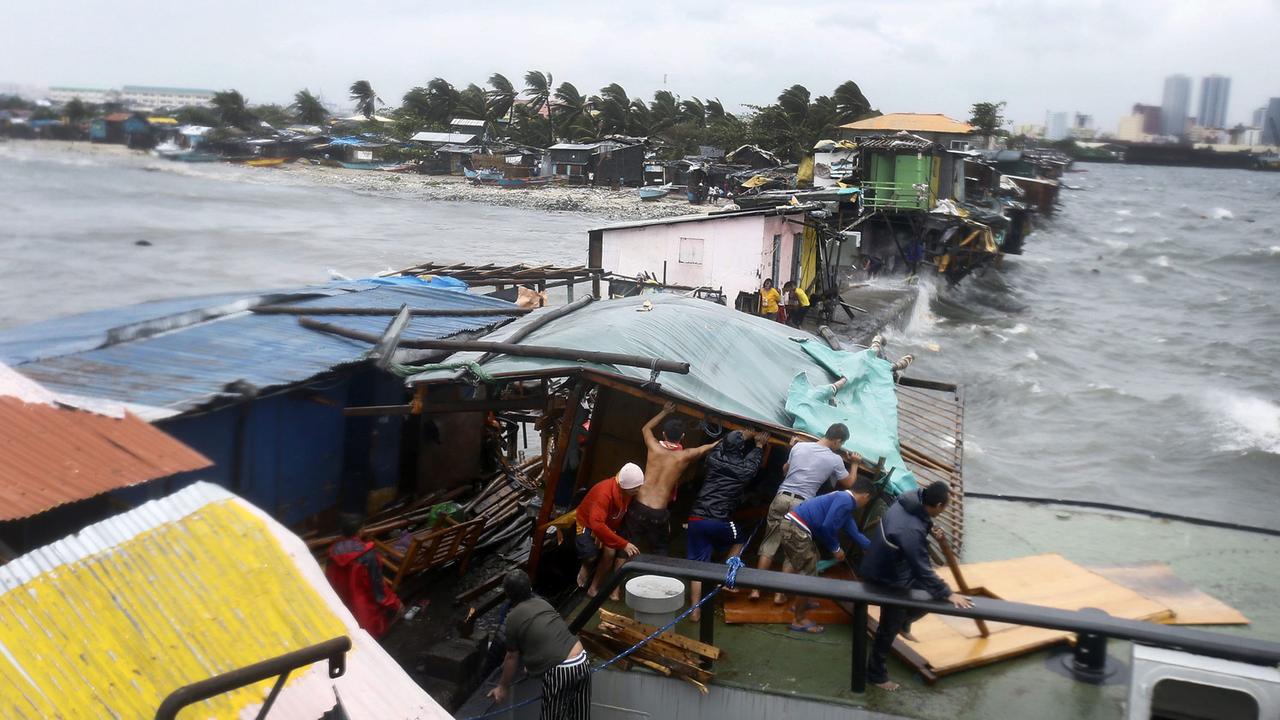 Die Bewohner eines an der Küste gelegenen Slums in der philippinischen Hauptstadt Manila reißen eine Baracke ein, die bei einem Taifun beschädigt wurde. Die Bewohner eines an der Küste gelegenen Slums in der philippinischen Hauptstadt Manila reißen eine Baracke ein, die bei einem Taifun beschädigt wurde.