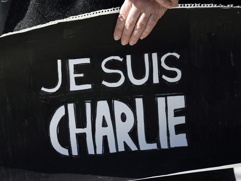 Eine Frau hält vor der französischen Botschaft in Tokio ein Schild mit "Je suis Charlie"