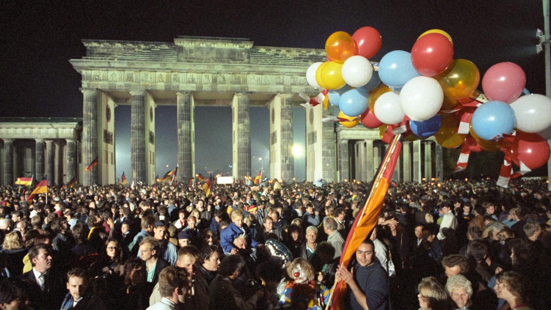 Ausgelassen feiert eine riesige Menschenmenge in der Nacht vom 2. auf den 3. Oktober 1990 vor dem Brandenburger Tor in Berlin die deutsche Wiedervereinigung.
