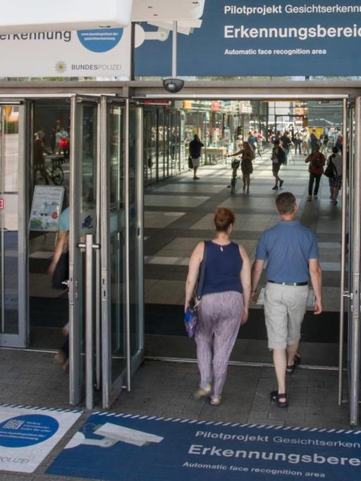 Zwei Personen betreten den Bahnhof Berlin-Südkreuz. Bodenaufkleber weisen am 01.08.2017 auf Erkennungsbereiche zur Gesichtserkennung hin.