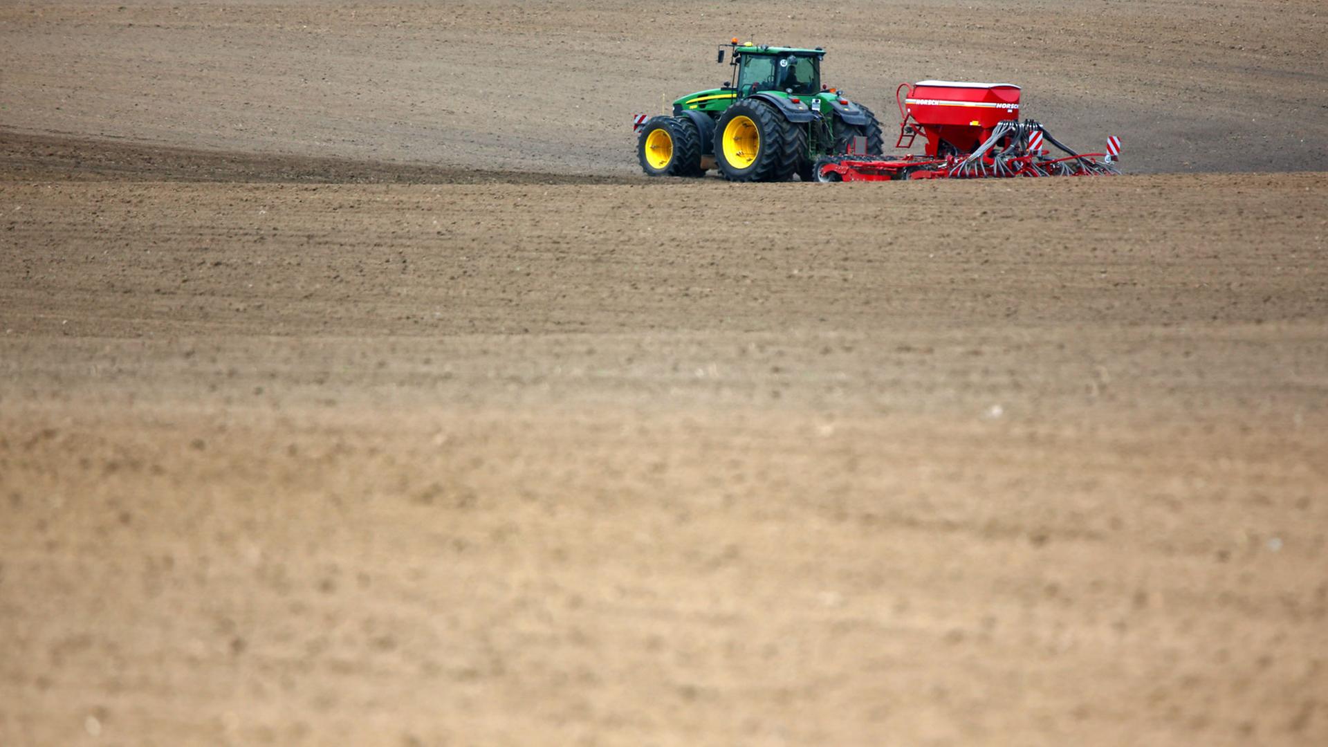 Ein Bauer düngt mit seinem Traktor einen Acker Ein Bauer düngt mit seinem Traktor einen Acker