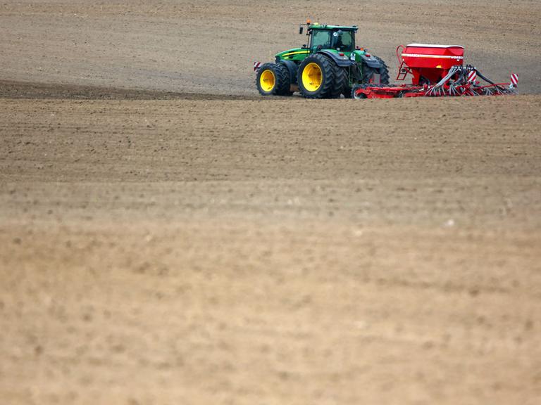 Ein Traktor mit einer Sämaschine fährt über einen Acker in der Nähe von Püttelkow (Mecklenburg-Vorpommern) und bringt Saatgut aus.