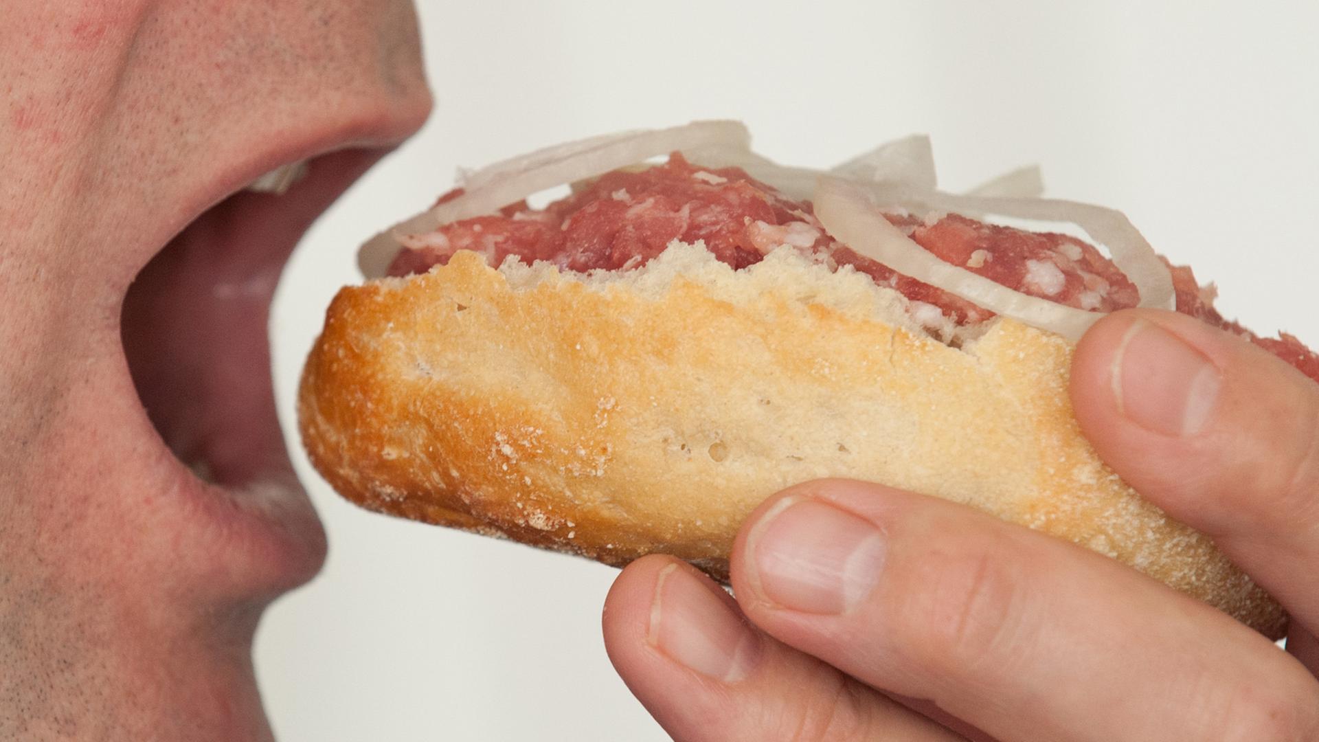 Ein Mann beißt in ein Mettbrötchen Ein Mann beißt in ein Mettbrötchen