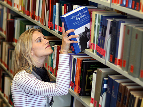 Eine Studentin nimmt ein Buch aus einem Regal in der Bibliothek des Romanischen Seminars der Ruhr-Universität in Bochum.