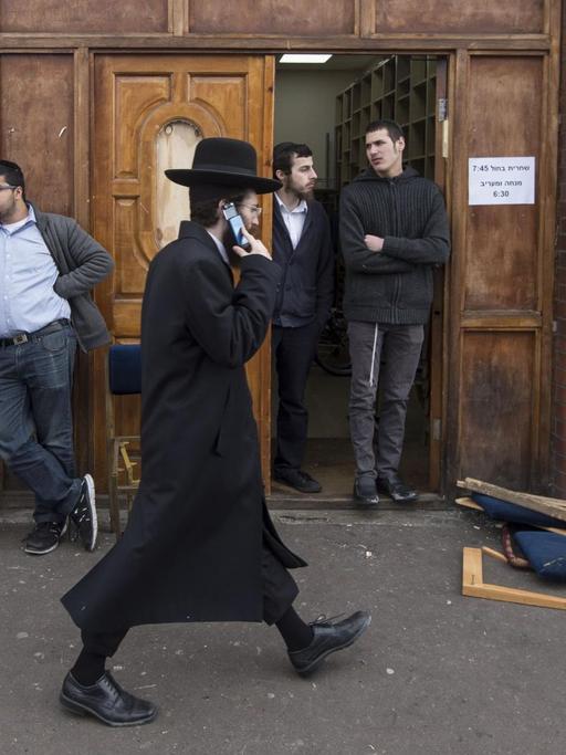 Ein orthodoxer Jude läuft telefonierend an der Ahavas Torah Synagoge in Stamford Hill im Norden Londons vorbei.