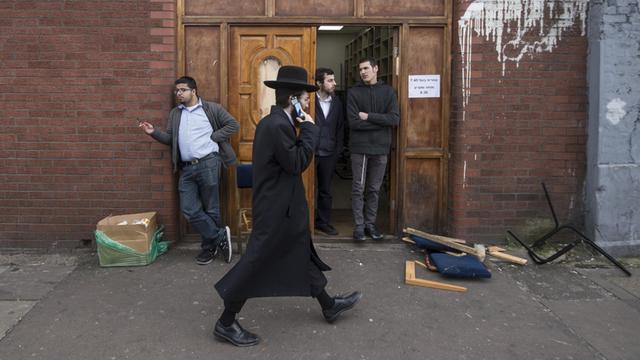 Ein orthodoxer Jude läuft telefonierend an der Ahavas Torah Synagoge in Stamford Hill im Norden Londons vorbei.