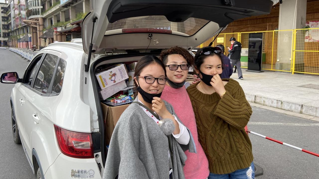 Drei junge Frauen stehen nebeneinander vor dem geöffneten Kofferraum eines Autos. Drei junge Frauen stehen nebeneinander vor dem geöffneten Kofferraum eines Autos.