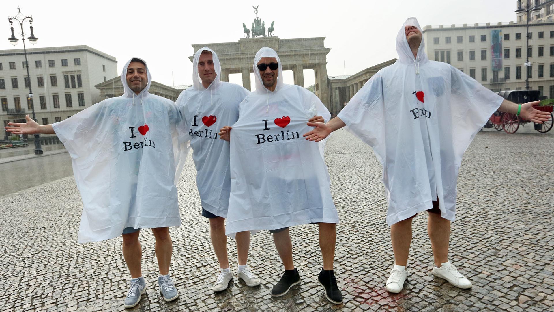 Touristen aus dem spanischen Barcelona stehen am 13.06.2015 vor dem Brandenburger Tor in Berlin bei Temperaturen um die 30 Grad im Regen. Foto: /dpa