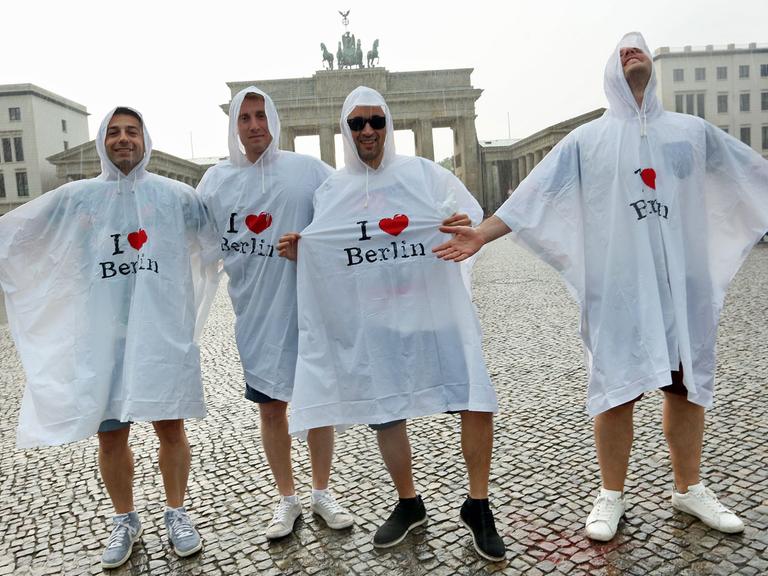 Touristen aus dem spanischen Barcelona stehen am 13.06.2015 vor dem Brandenburger Tor in Berlin bei Temperaturen um die 30 Grad im Regen. Foto: /dpa