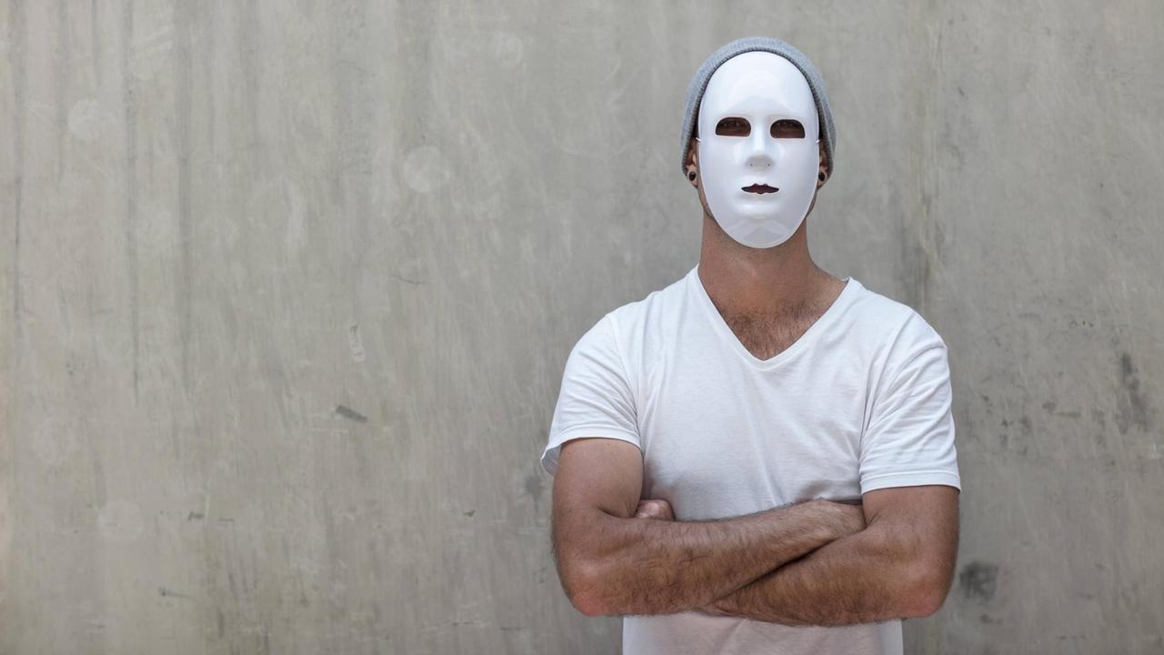 Ein Mann mit weißer Maske und verschränkten Armen steht vor einer Beton...</p>

                        <a href=