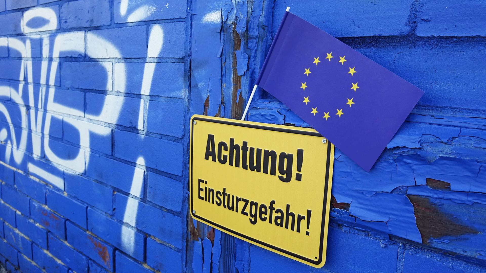Eine EU-Flagge steckt an einem Hinweisschild mit der Aufschrift "Achtung! EInsturzgefahr!", aufgenommen am 12.02.2017 in Borkheide in Brandenburg.