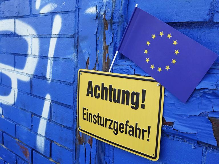 Eine EU-Flagge steckt an einem Hinweisschild mit der Aufschrift "Achtung! EInsturzgefahr!", aufgenommen am 12.02.2017 in Borkheide in Brandenburg.