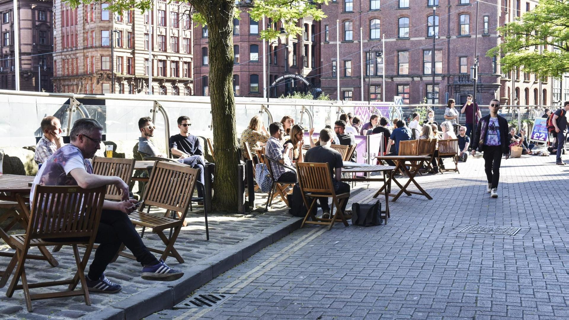 Menschen sitzen auf einer Terasse auf der Canal Street in Manchester. Das Leben scheint nach dem Terroranschlag auf ein Popkonzert wieder normal weiter zu gehen. 22 Menschen waren dabei am Montagabend getötet und Dutzende verletzt worden. Menschen sitzen auf einer Terasse auf der Canal Street in Manchester. Das Leben scheint nach dem Terroranschlag auf ein Popkonzert wieder normal weiter zu gehen. 22 Menschen waren dabei am Montagabend getötet und Dutzende verletzt worden.