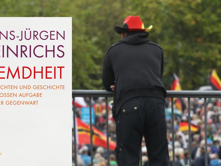 Ein Mann mit einem Cowboyhut in den Farben der Deutschlandfahne lehnt an einem Geländer und betrachtet eine nationalkonservative Demonstration in Dresden.