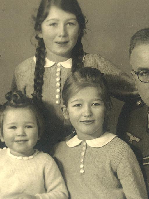 Schwarzweißes Familienfoto. Ein Mann in Uniform mit seiner Frau und drei Kindern.