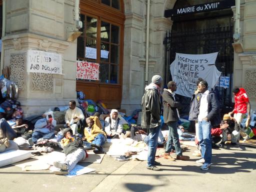 Flüchtlinge stehen, sitzen und liegen vor dem Verwaltungsgebäude des 18. Arondissements in Paris.