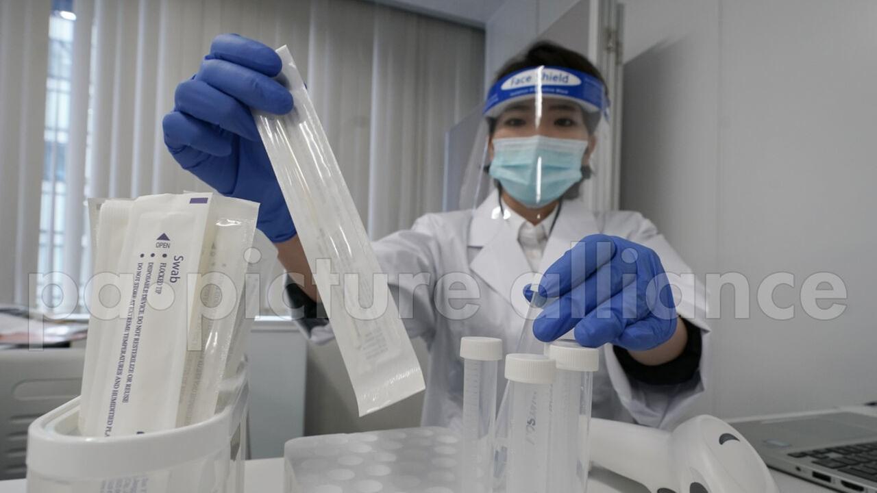 Ein Testzentrum in Tokio - eine Frau in Schutzkleidung hält Teststäbchen in der Hand. Ein Testzentrum in Tokio - eine Frau in Schutzkleidung hält Teststäbchen in der Hand.