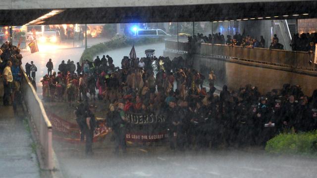 Menschenmenge in einer Straßenunterführung, davor regnet es.